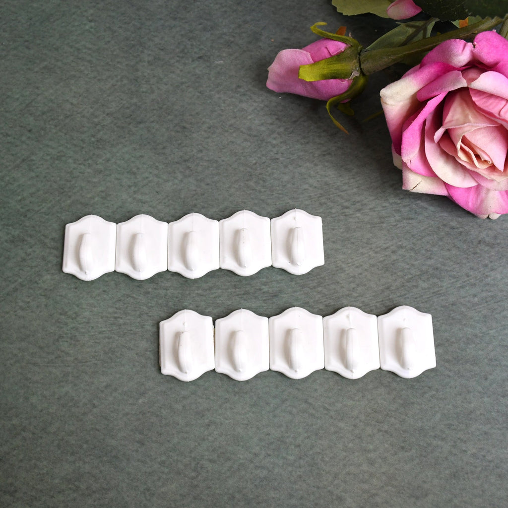 Set of 10 white plastic adhesive wall hooks for drill-free hanging.