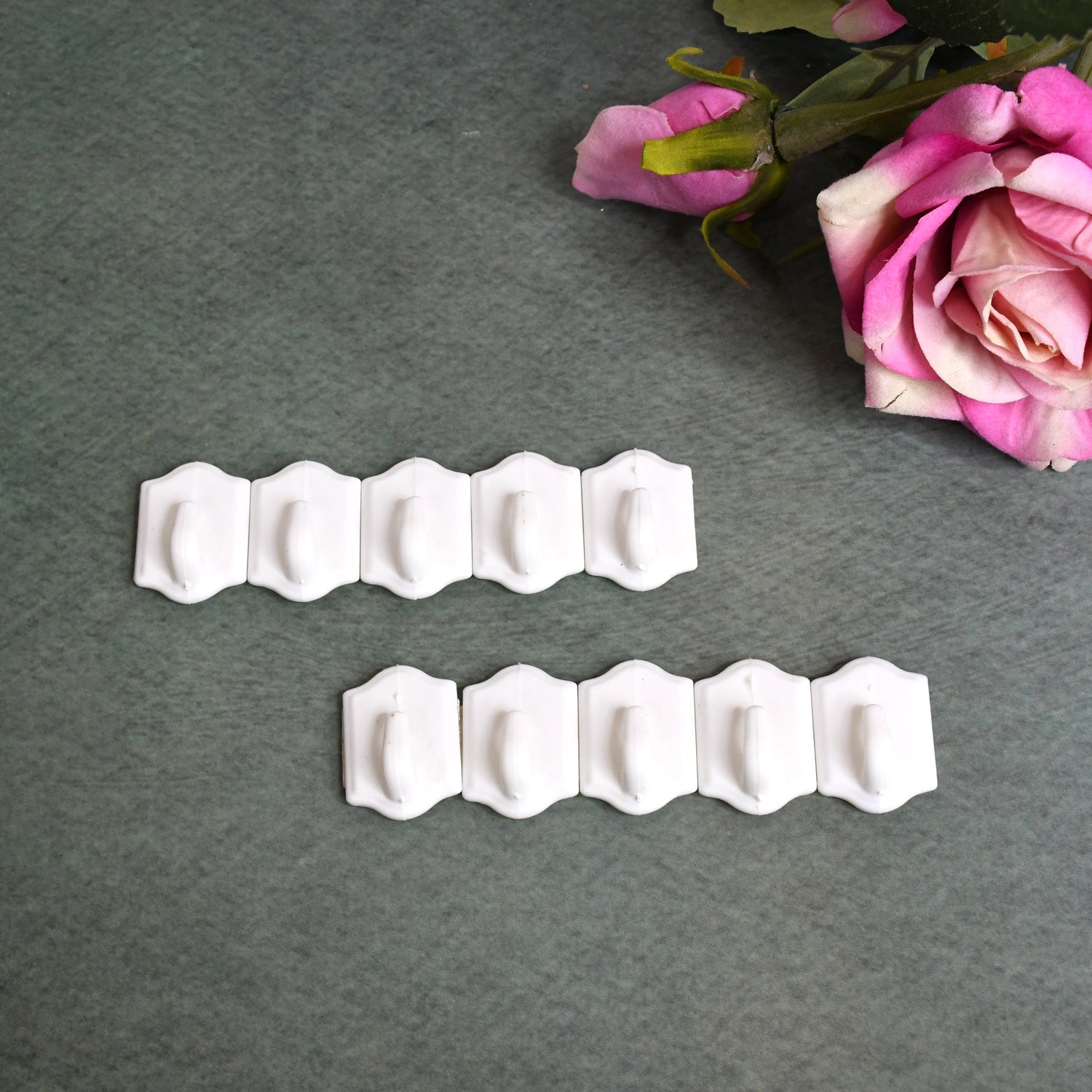 Set of 10 white plastic adhesive wall hooks for drill-free hanging.