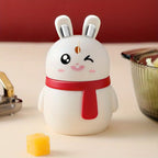 A red rabbit toothpick dispenser with an automatic press mechanism on a wooden table.