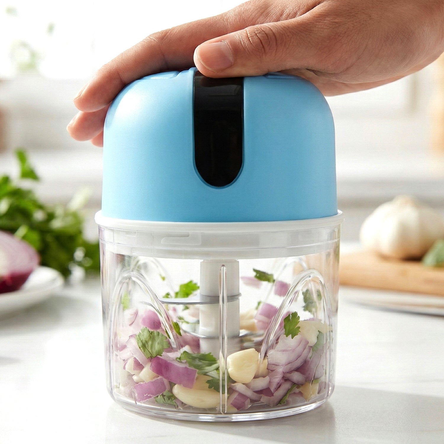 Mini electric garlic chopper on a kitchen counter, demonstrating its compact size.