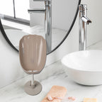 Self-draining soap holder in a bathroom, neatly holding a bar of soap and a scrubber.