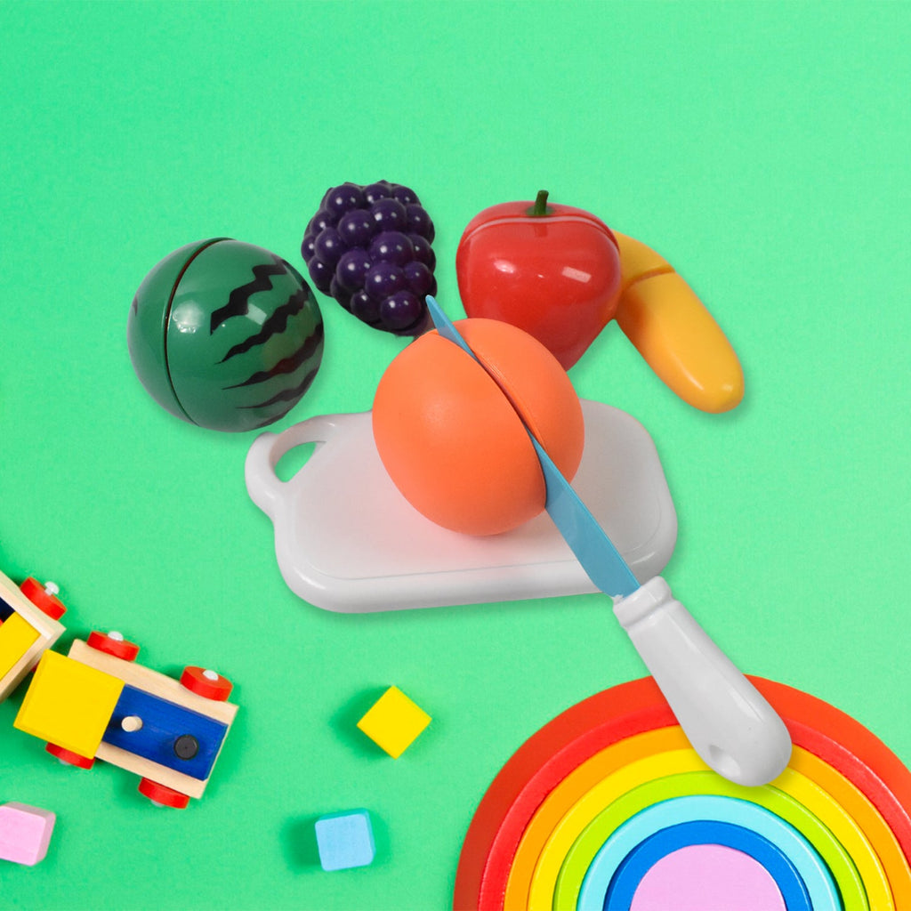 Child happily playing with Aditi fruit cutting toy set, slicing a toy apple.