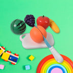 Child happily playing with Aditi fruit cutting toy set, slicing a toy apple.