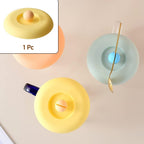 A Tidy Table Silicone Cup Lid in grey, providing an airtight, dust-proof seal on a ceramic mug.