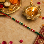 Red and Green Thread Rakhi with White Beads showing traditional design