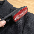 Close-up of lint remover double sided brush capturing dust and lint from clothes