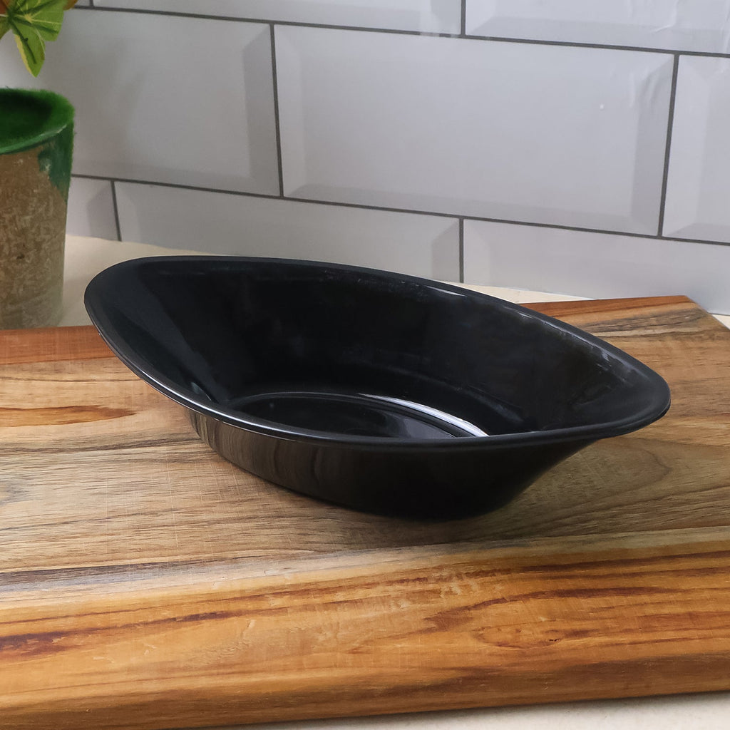 Angled view of deep oval black Marin plastic serving bowl