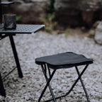 Portable camping stool shown folded, highlighting its slim profile for transport.