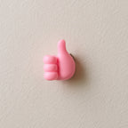 Pink hand-shaped wall clip holder made of silicone on white background