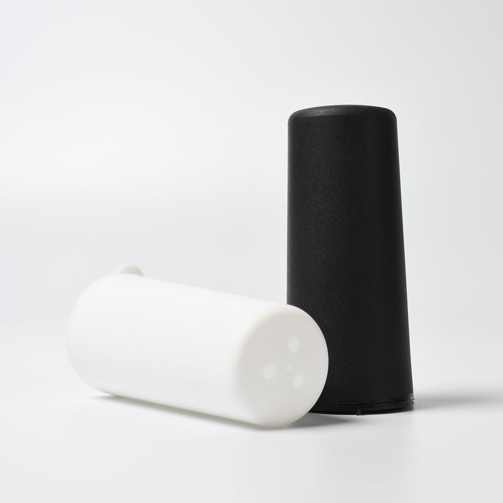 Polycarbonate spice dispensers pouring salt and pepper onto a dish.