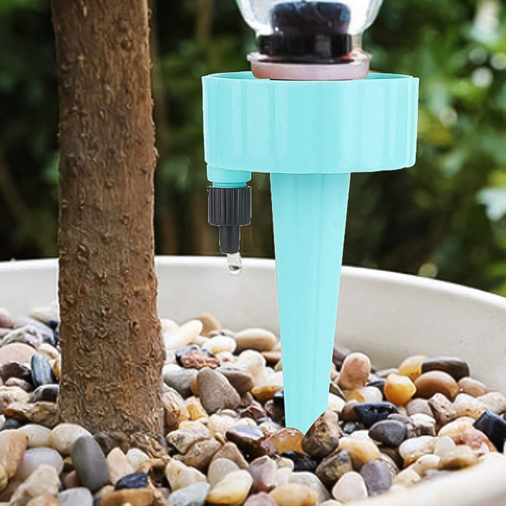 An auto plant watering device in action, slowly releasing water into a plant pot from a recycled bottle.