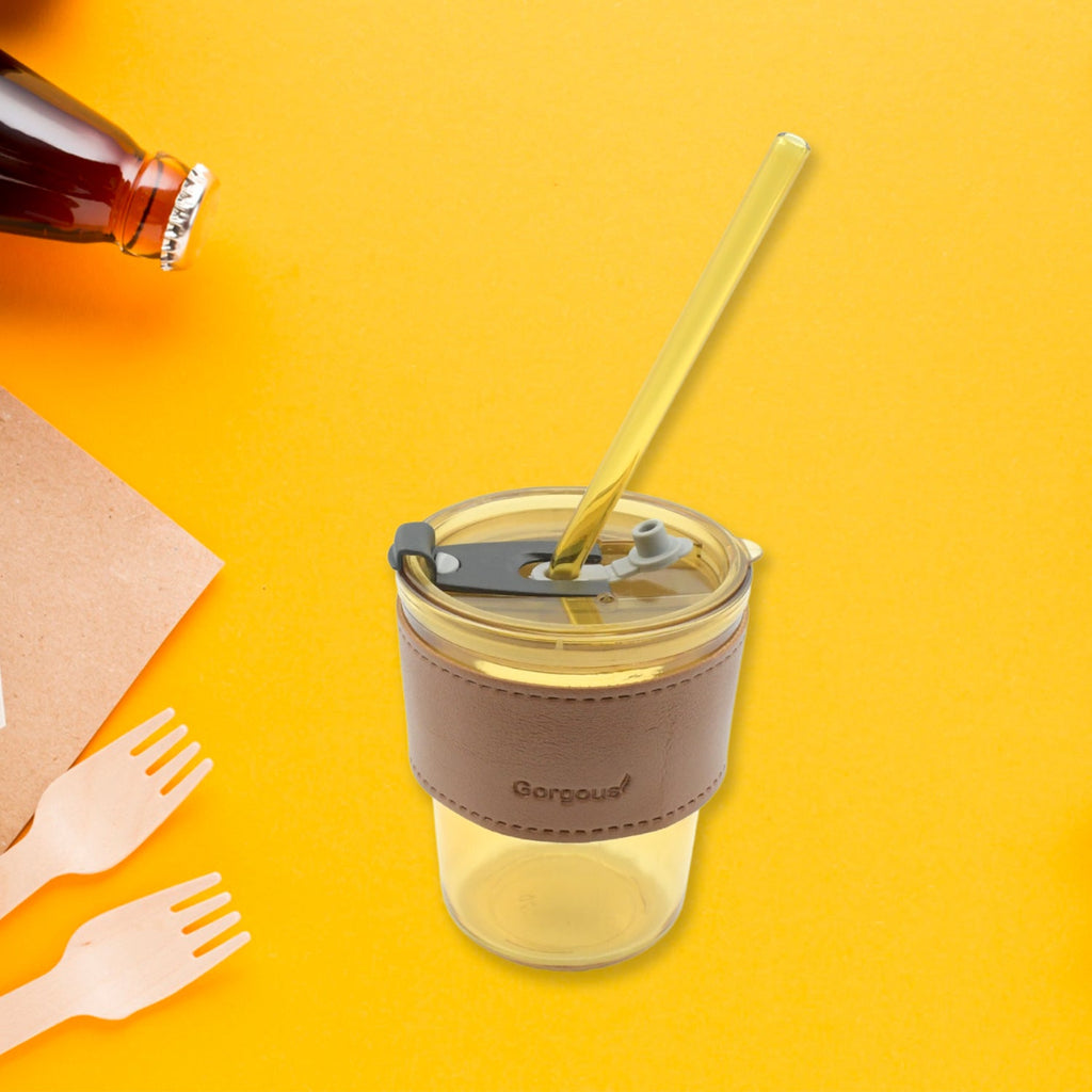 Clear glass coffee mug with lid and reusable straw, ideal for travel.