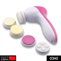 Pink 5-in-1 facial massager with multiple attachments on a clean surface.