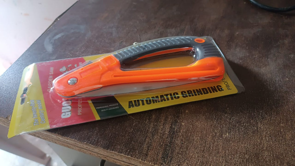 A versatile Folding Pruning Saw resting in a vibrant garden, ready for various pruning tasks.