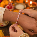 Angled view of Pink & White Thread Rakhi on a white surface