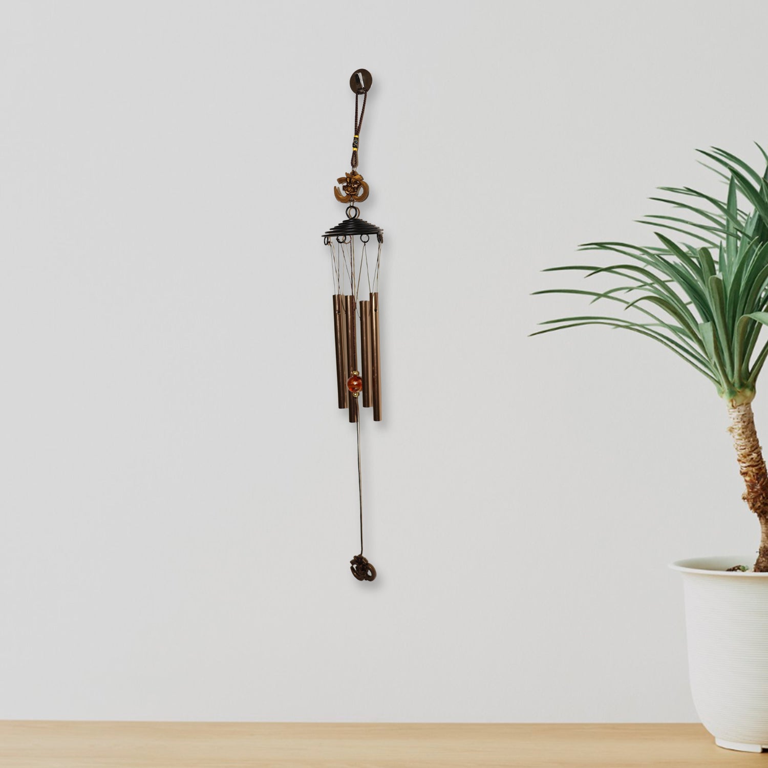 Close side shot of metal wind chime with Om symbol and metal tubes