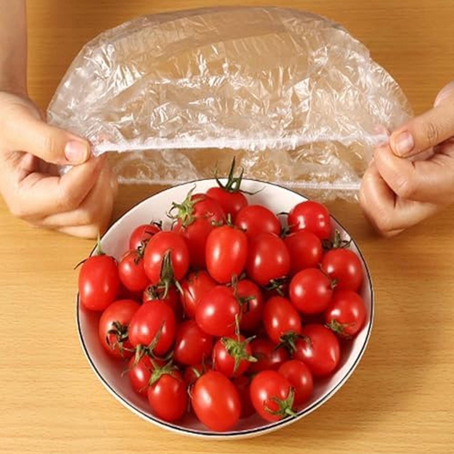 An elastic food cover keeping a plate of sliced fresh fruits perfectly sealed.