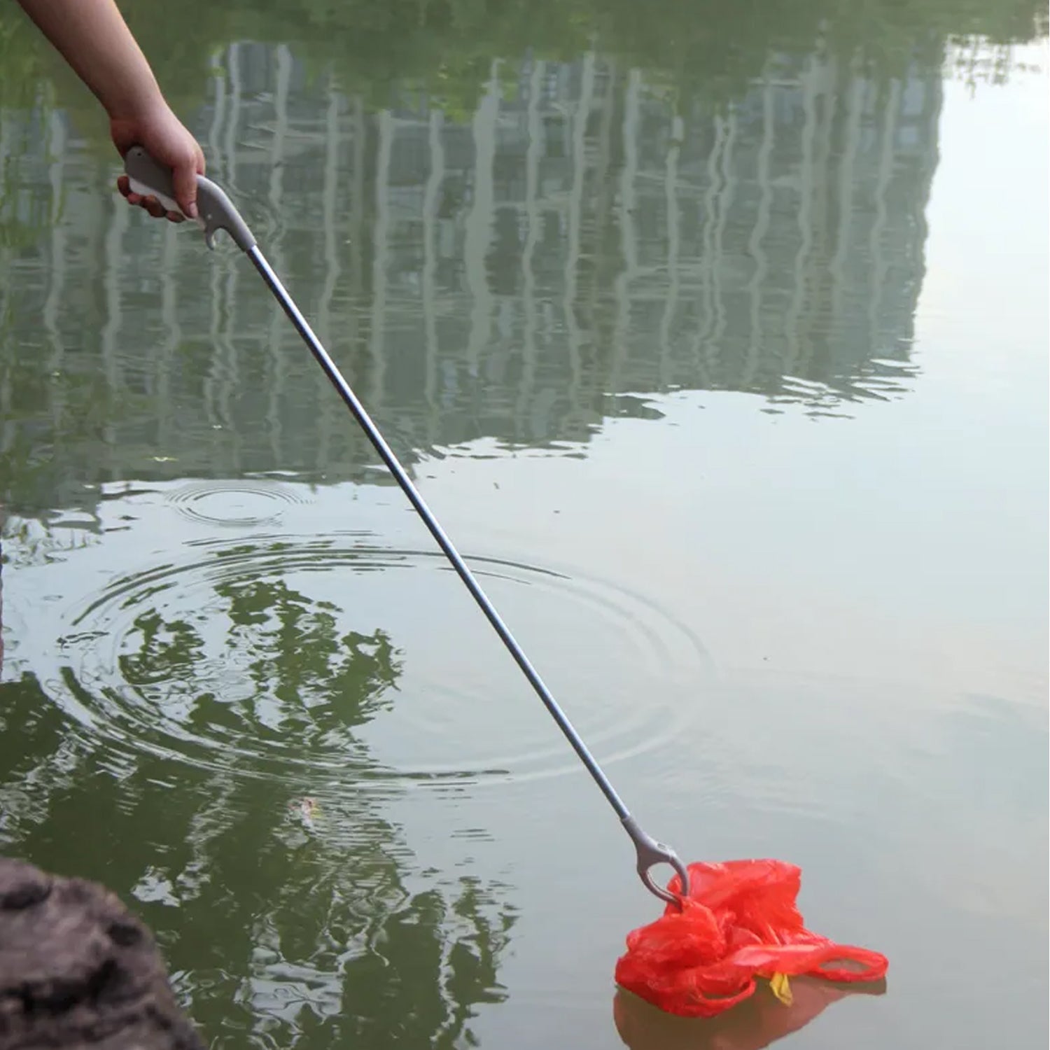 Flexible garbage picker tool with yellow handle, extended for reaching.
