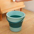 A blue foldable water bucket with a handle, shown partially collapsed.
