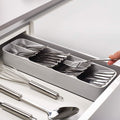 An empty, grey plastic cutlery tray with multiple compartments for kitchen drawer organisation.