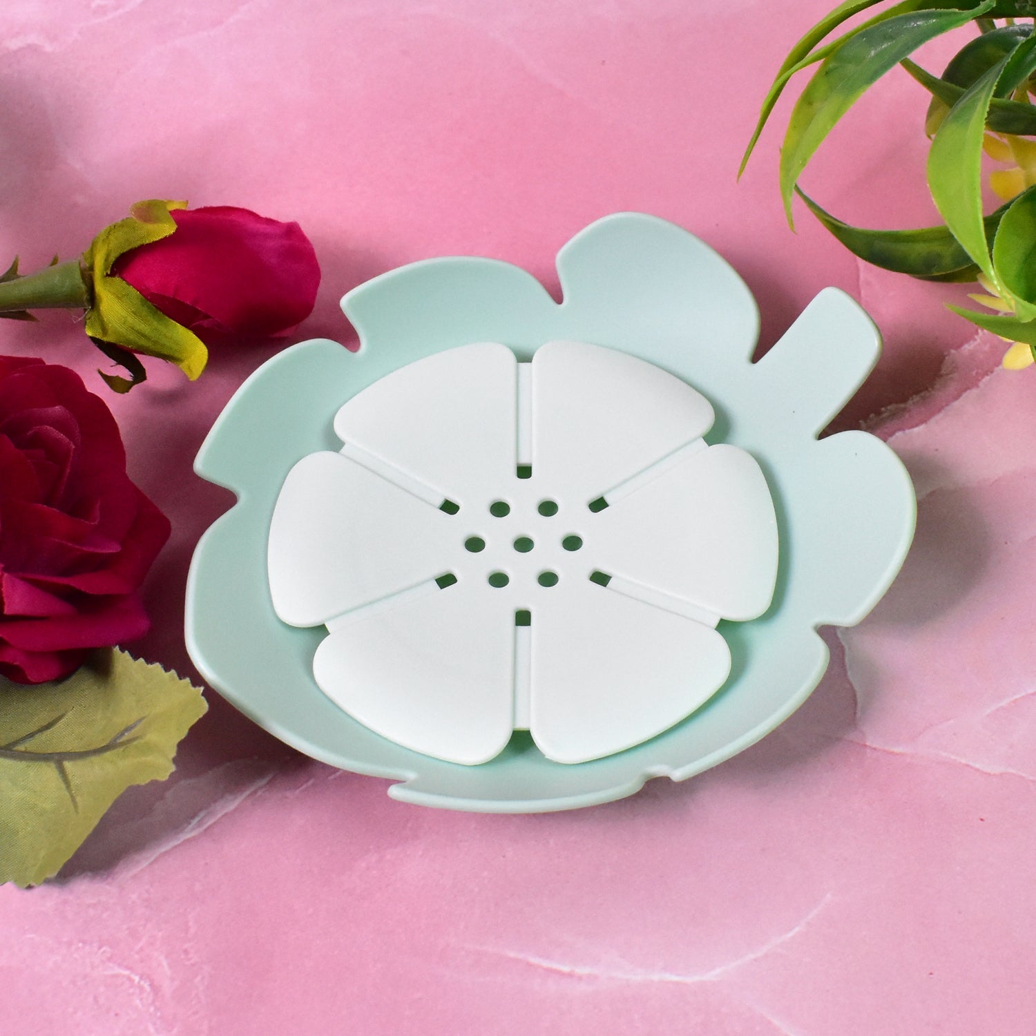 Set of two floral plastic soap dishes, one white and one pink, in a bathroom.