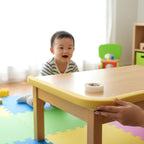 A toddler safely playing near a table protected by a corner guard.