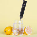 Electric handheld milk frother with stainless steel whisk in use