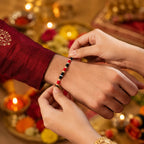 Elegant red and black thread rakhi with white beads and golden detailing