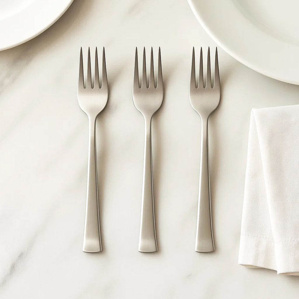 Stainless steel dining forks arranged on a table, ready for a meal setting.