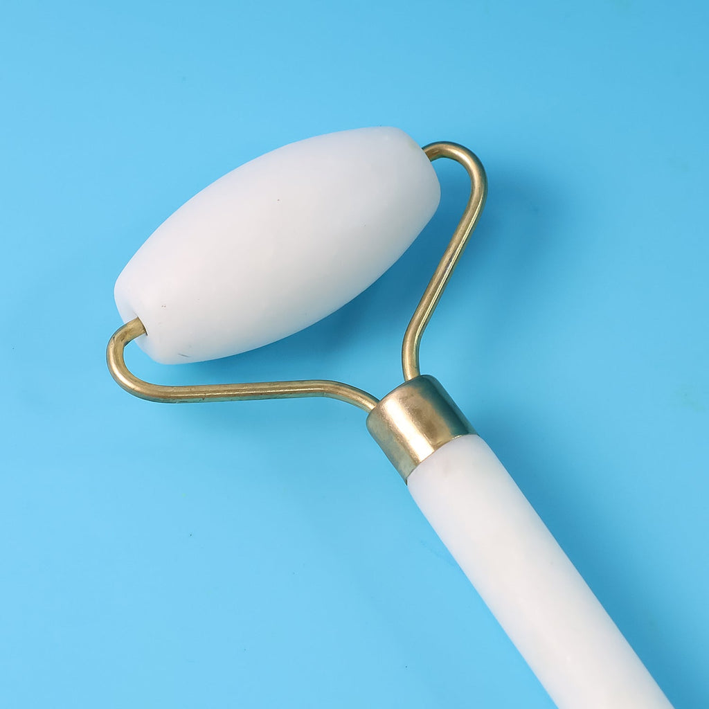 Woman demonstrating use of the dual-ended face massage roller for facial massage.