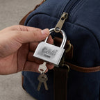 Heavy steel padlock and its keys displayed on a rustic wooden surface.