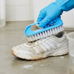Stiff bristle scrub brush cleaning bathroom floor tiles with powerful scrubbing action.