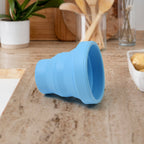 Flexible silicone travel mug in purple, held by hand, highlighting its ergonomic design.