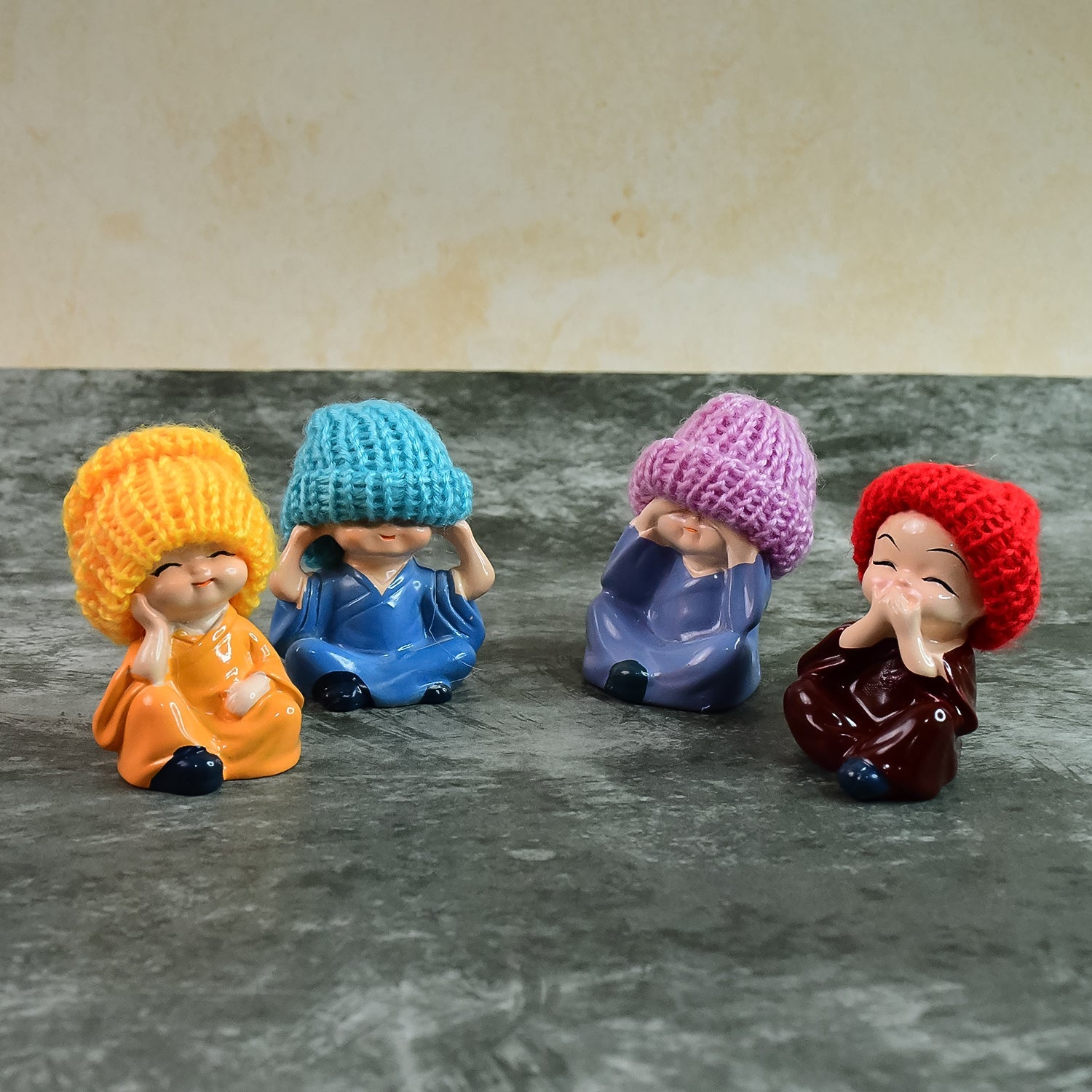Four resin monk Buddha mini statues arranged side-by-side showcasing traditional poses