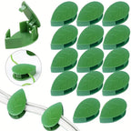 Detail view of a green leaf-shaped plant climbing clip with its adhesive side visible.