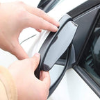 Hand applying adhesive side mirror shield to a car's side mirror.