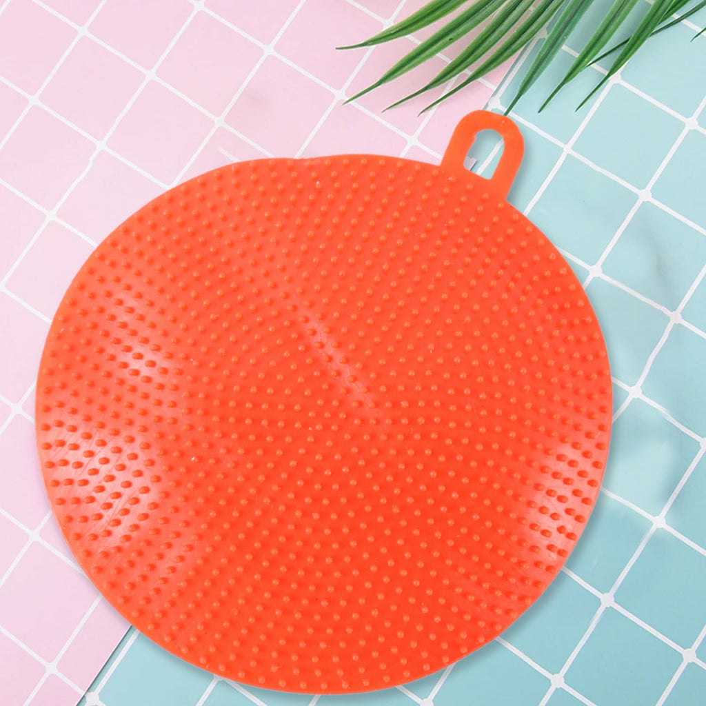 Red silicone dish scrubber hanging to dry after washing