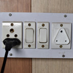 Image showing how to install a child safety outlet plug into a standard electrical socket.