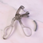 Transparent eyelash curler viewed from side angle showing smooth press