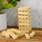 A child's hands attempting to extract a block from the precarious wooden tower during a game.