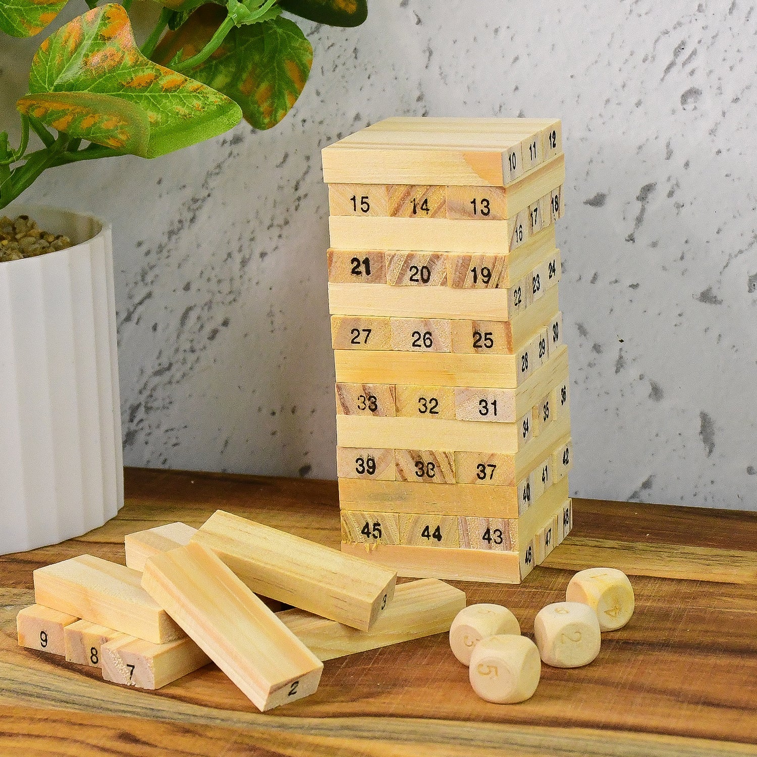 A child's hands attempting to extract a block from the precarious wooden tower during a game.