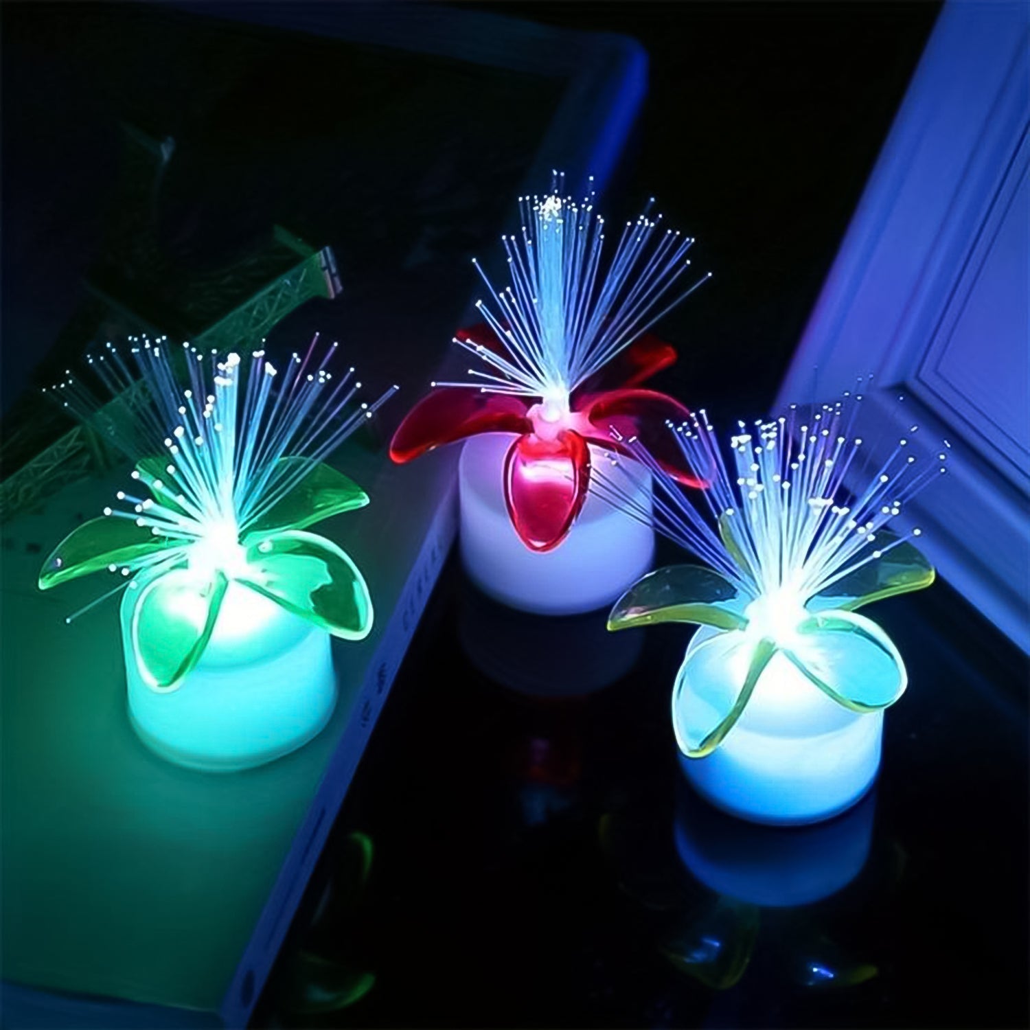 A group of fiber optic LED centerpieces illuminating a dark room.