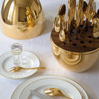 Elegant 24-piece golden cutlery set with an oval stand on a dining table.