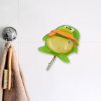 Multiple decorative self-adhesive wall hooks organizing kitchen utensils.
