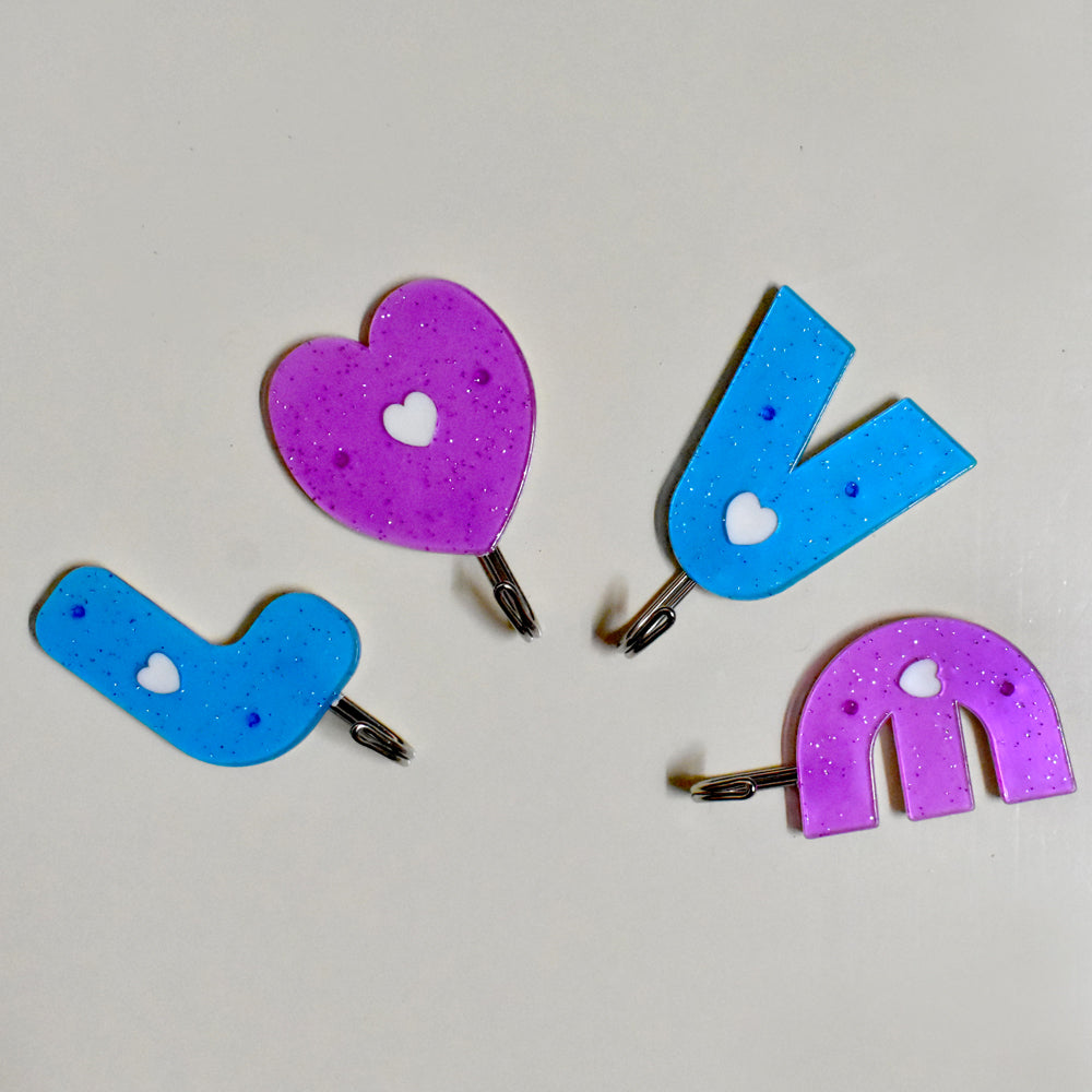 Love shape self adhesive hooks in white, mounted on a wall.