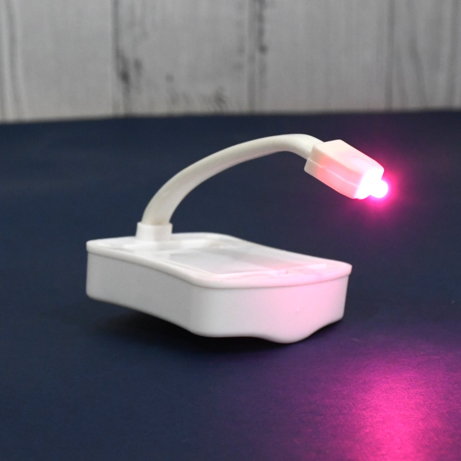 Hand holding the battery-operated LED toilet light, highlighting its portable design.