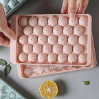 The  ice ball mold alongside a glass of chilled beverage, ready for serving.