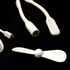 A mini USB fan plugged into a laptop, demonstrating its convenient use for personal cooling.