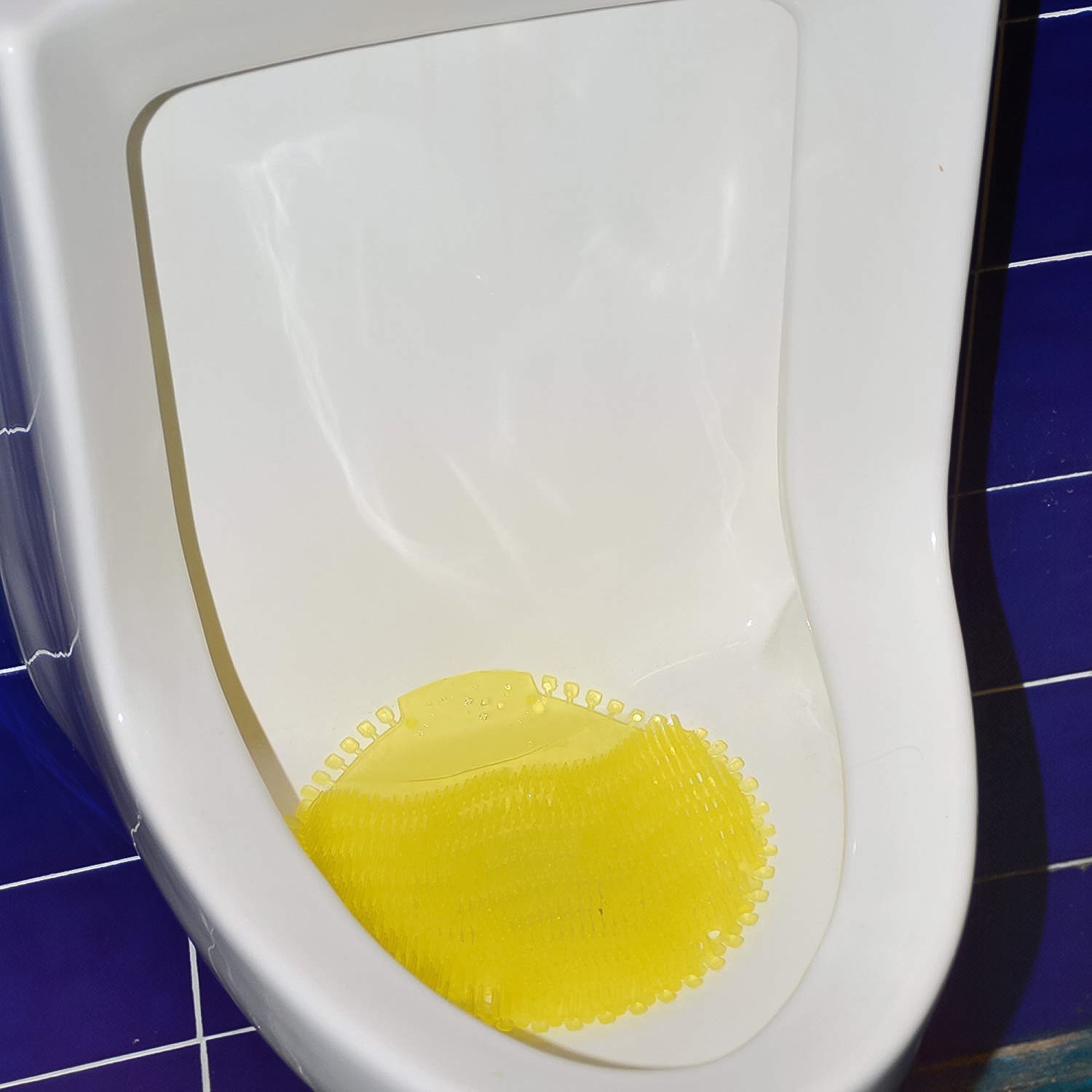 Urinal screen deodorizer mat placed inside urinal for splash control and odor freshness.