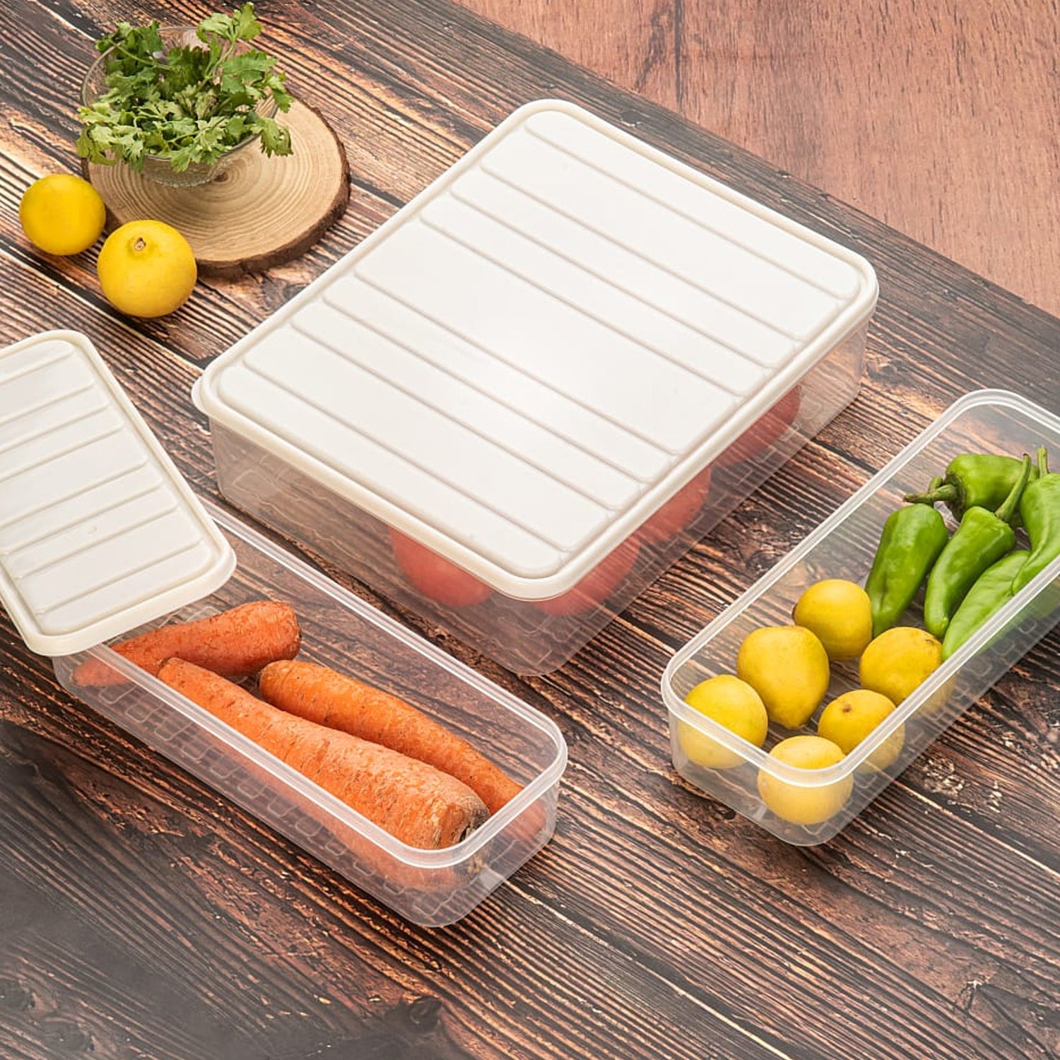 A set of three transparent plastic food storage containers with blue lids, stacked neatly in a fridge.